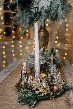 A candle in a candlestick decorated in a Christmas theme. A decor concept for home decoration for the New Year holidays, table decoration for Christmas.