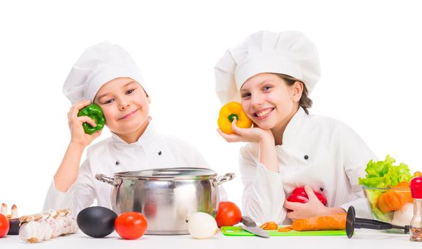 little smiling girl and boy with pan and ingredients for soup on kitchen table
