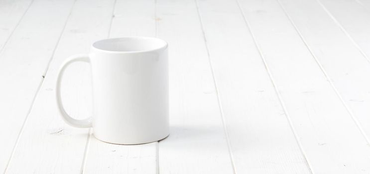 white empty cup on white planked wooden table