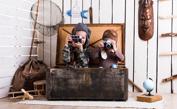 two little girls in hats in big wooden chest playing rarity cameras