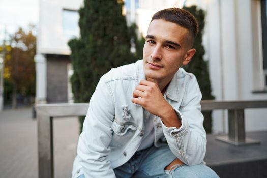 Young casual man sitting on stairs alone on city street