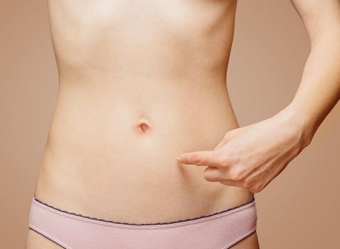 Woman points to a thin abdomen, space for text, face is not visible