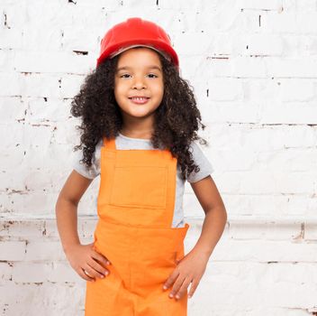 cute little girl in orange repairmen uniform and helmet