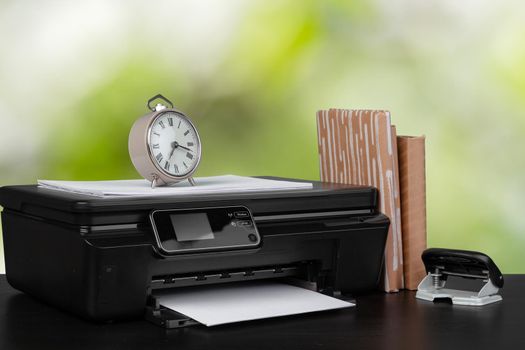 Stack of books and home printer against blurred background, close up