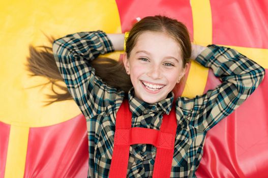 smiling joyful girl lying on colorful trampoline in entertainment center
