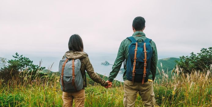 Hiker couple in love holding hands each other and enjoying view island in the sea