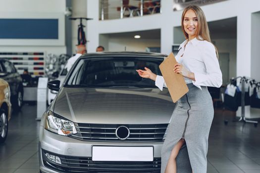 Happy beautiful young woman car dealer in showroom close up