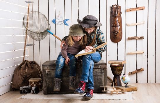 two cute little girls in cowboy hats sitting on wooden chest and watching album