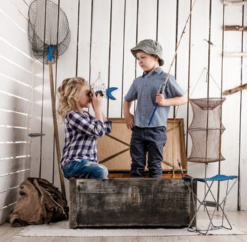 little boy taking picture of cute little girl sitting on big old chest