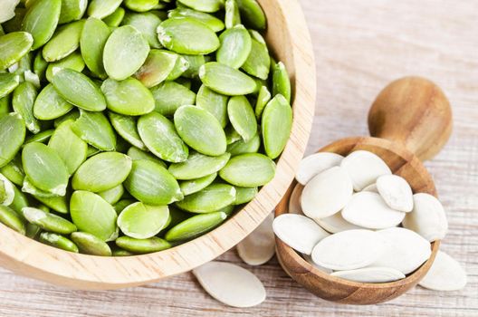 Pumpkin seeds green and unpeeled in wooden bowl.