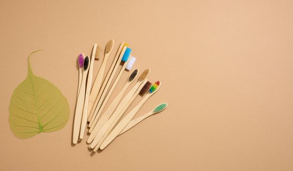 multicolored wooden toothbrushes on a brown background, plastic rejection concept, zero waste, top view