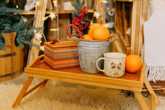 Tangerines, a gift box and Christmas decorations, lollipops on the table. The concept of a New Year's home decor.