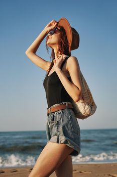 cheerful woman in a hat with sunglasses walking with a bag. High quality photo