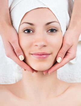 beautiful young woman enjoying facial massage procedure in spa