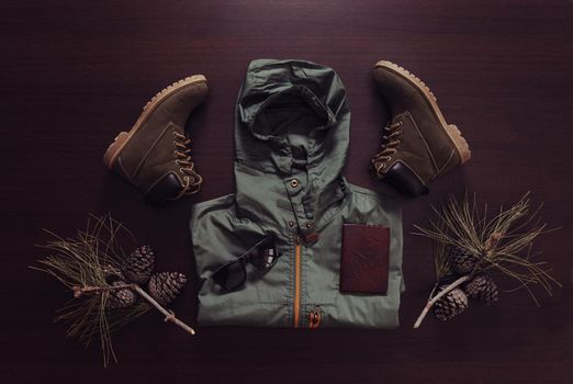 Set of outfit for traveler man on wooden background, top view