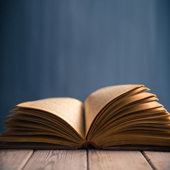 Empty open book on a wooden table on a background of blackboard, copyspace