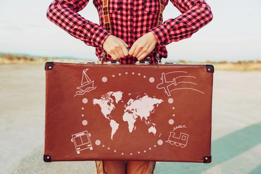Traveler woman standing with a suitcase. Map of the world and types of transport are painted on suitcase. Concept of travel