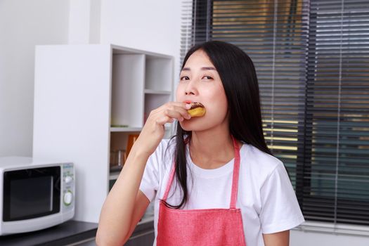 woman eating a chocolate donut in kitchen room at home