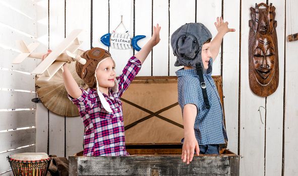 two little children-pilots fly with hands sitting in big old chest