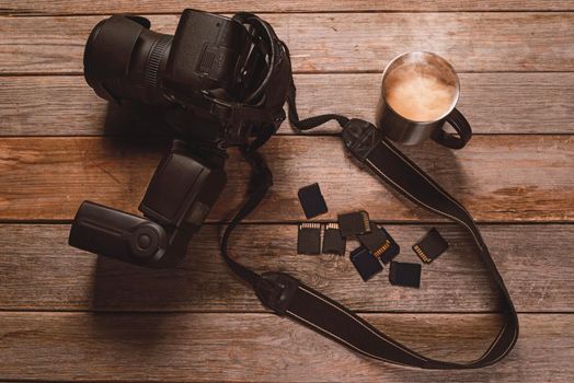 Digital photo camera, memory cards and cup of coffee on wooden table