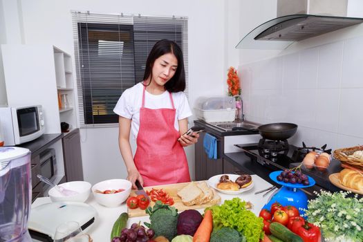 woman using mobile phone and cooking in the kitchen room