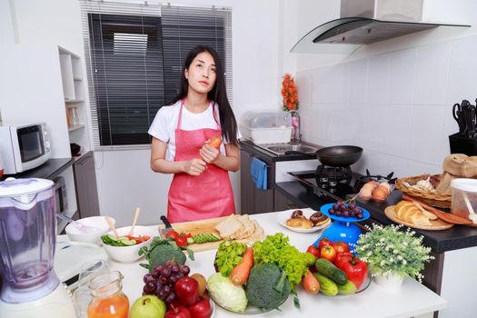 woman holding a carrot in kitchen room at home