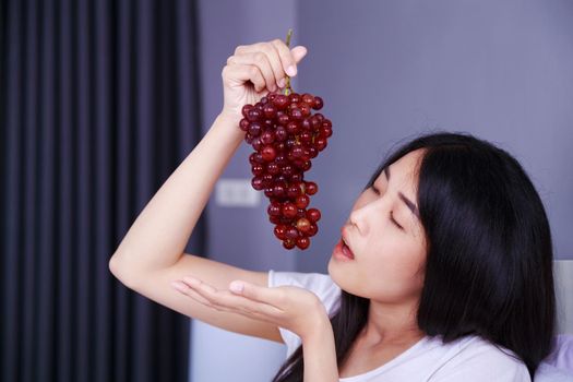 woman with red grape on bed in the bedroom