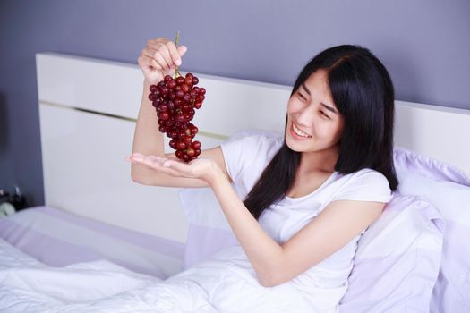 woman with red grape on bed in the bedroom