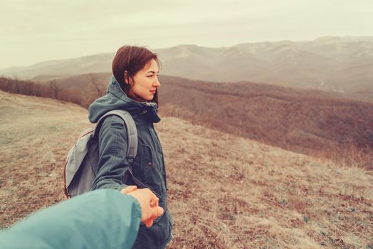 Hiker woman holding man's hand on nature in the mountains. Couple in love. Focus on woman. Point of view shot
