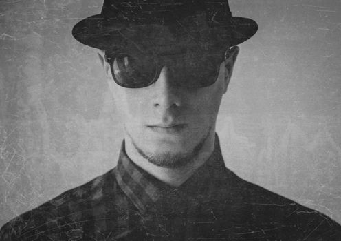 Portrait of serious man in sunglasses and hat. Image with old effect, textured image. Black and white image