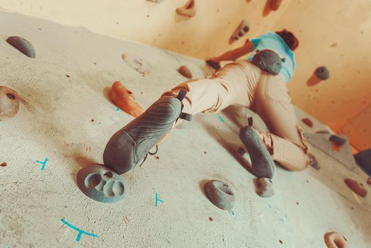 Woman climbing artificial boulder indoors, view from below