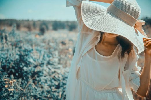 Attractive woman in hat with wide brim walking in fantastic park