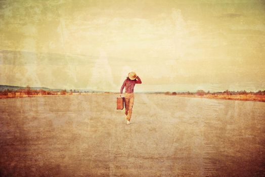 Traveler woman is running with suitcase on road. Vintage image