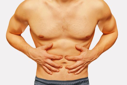 Unrecognizable man compresses the abdomen due to pain on a white background