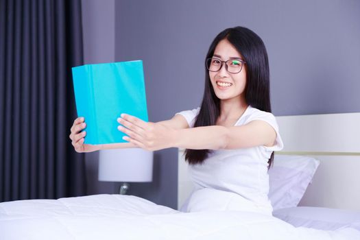 woman reading a book on bed in the bedroom at home