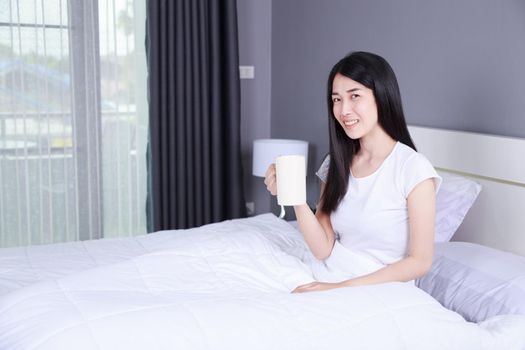 woman on bed with a cup of coffee in the bedroom