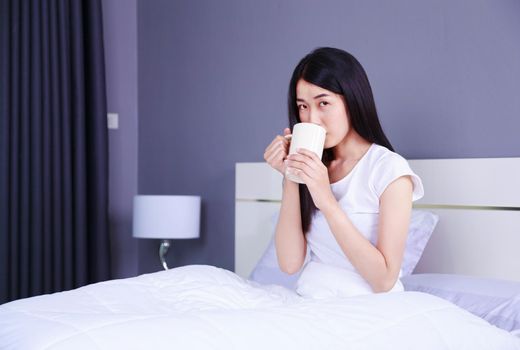 woman on bed with a cup of coffee in the bedroom