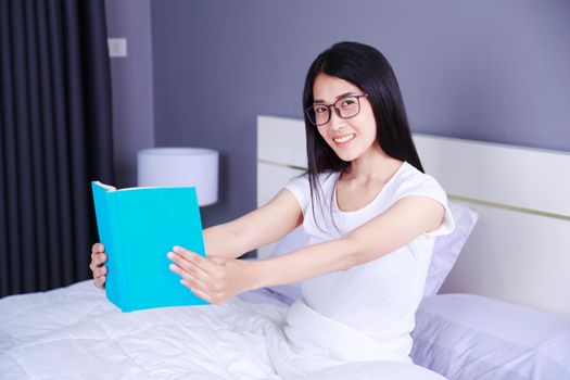 woman reading a book on bed in the bedroom at home