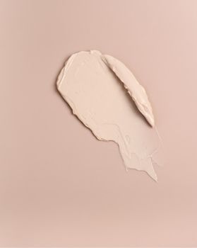 Pink creamy foundation texture background. A smear of ivory foundation on a pink background.