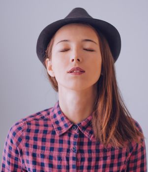 Portrait of beautiful hipster girl with closed eyes in a hat and plaid shirt. Focus on lips