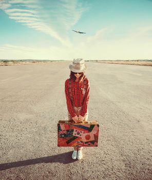 Woman traveler holds vintage suitcase on the runway