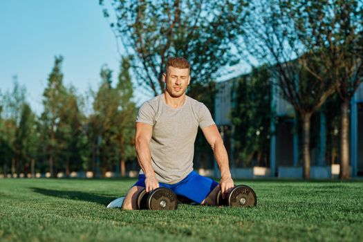 athletic man with dumbbells in the park exercise motivation. High quality photo