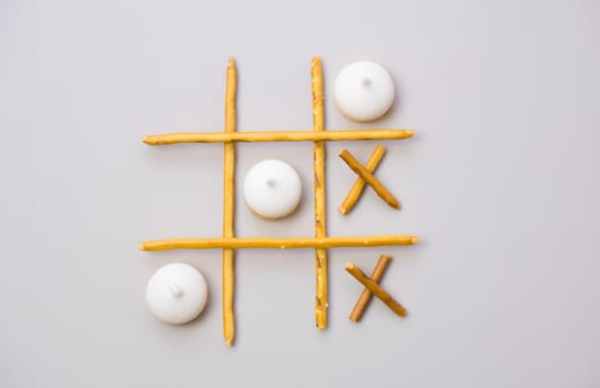 tic-tac-toe from crackers and sticks on a gray background. Food concept. Edible snacks dry sticks with salt and cookies on a white plate. Straws, sticks for crackers