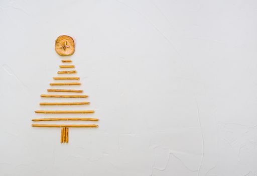 Christmas tree made from pepero straws cookies, on white background texture. Top view with space for text on the right.