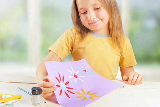 Little girl looks on a handmade greeting card for mothers day