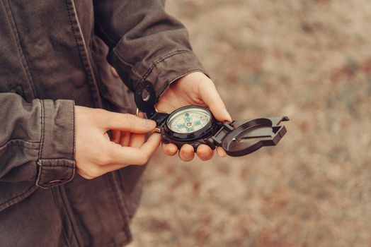 Hiker woman searching direction with a compass outdoor. View of hands