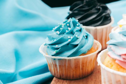 Close up of some decadent gourmet cupcakes frosted with a variety of frosting flavors