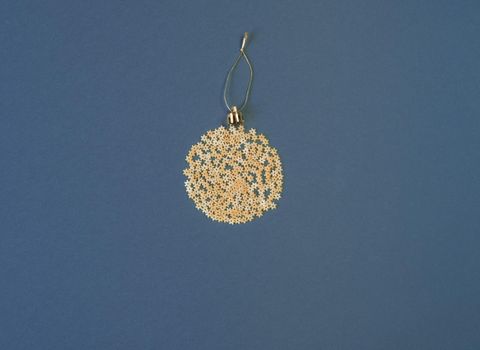 Christmas decoration on a tree in the form of a ball of pasta on a blue paper background, top view. Conceptual photo