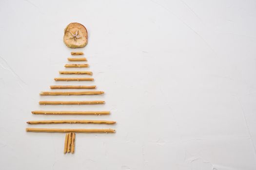 Christmas tree made from pepero straws cookies, on white background texture. Top view with space for text on the right.