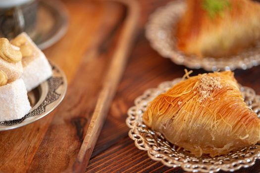 Turkish sweets on small plate on brown wooden background, close up